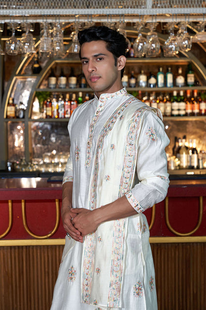 Indian man wearing a white embroidery work kurta with a duppata.