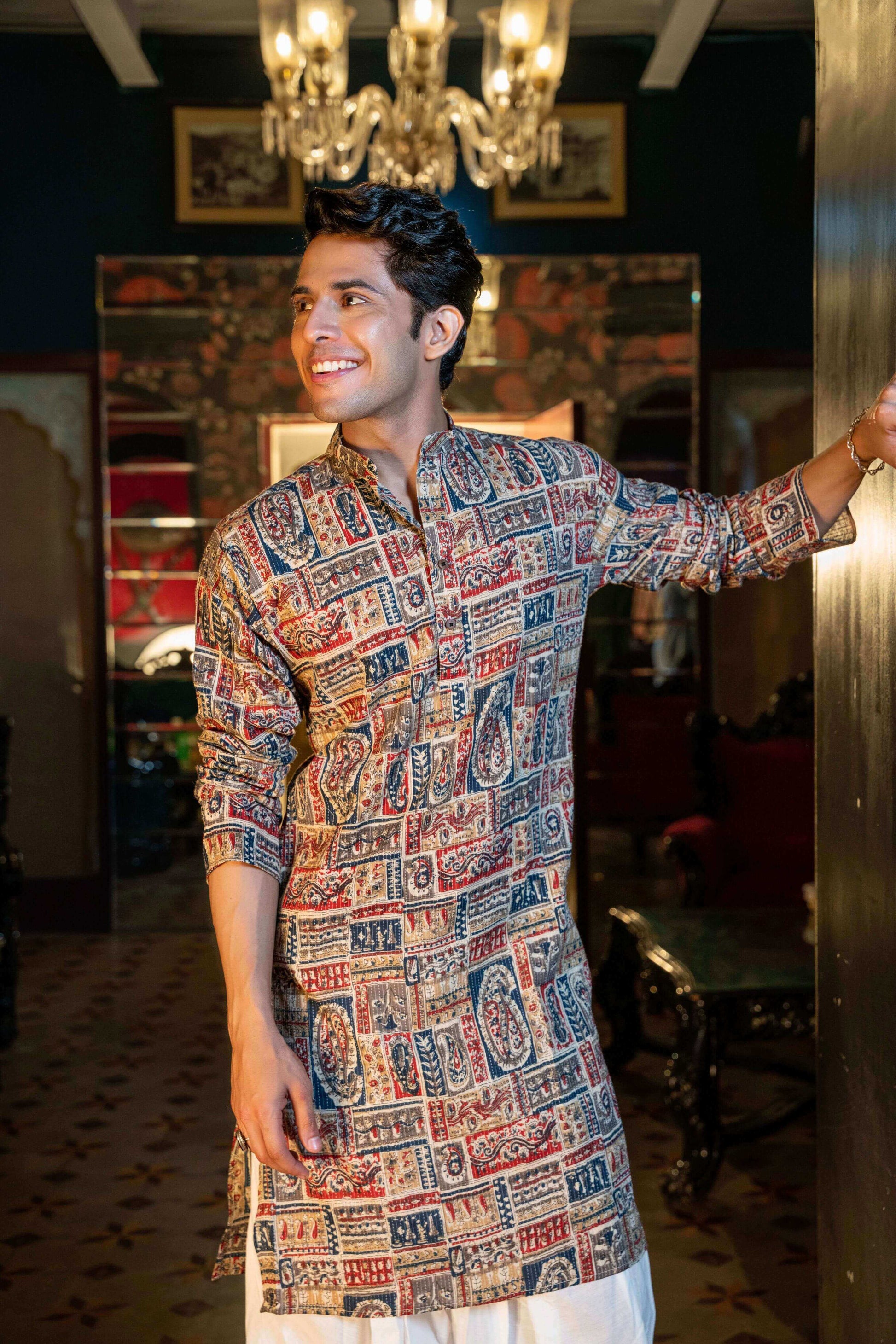 Indian man wearing a traditional kurta and featuring patchwork and vibrant colors. 