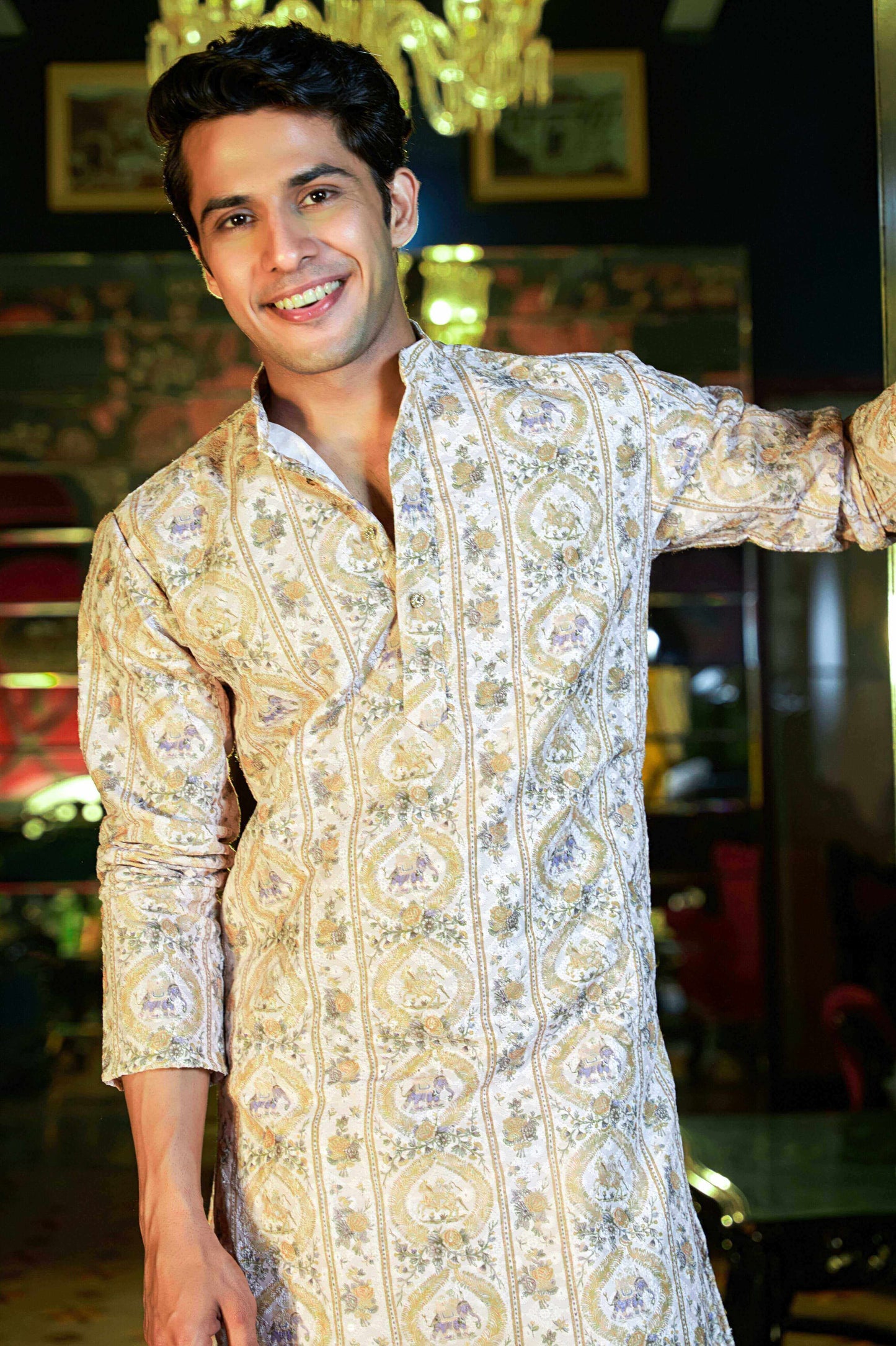 A man wearing a white kurta,  standing confidently with a neutral expression.