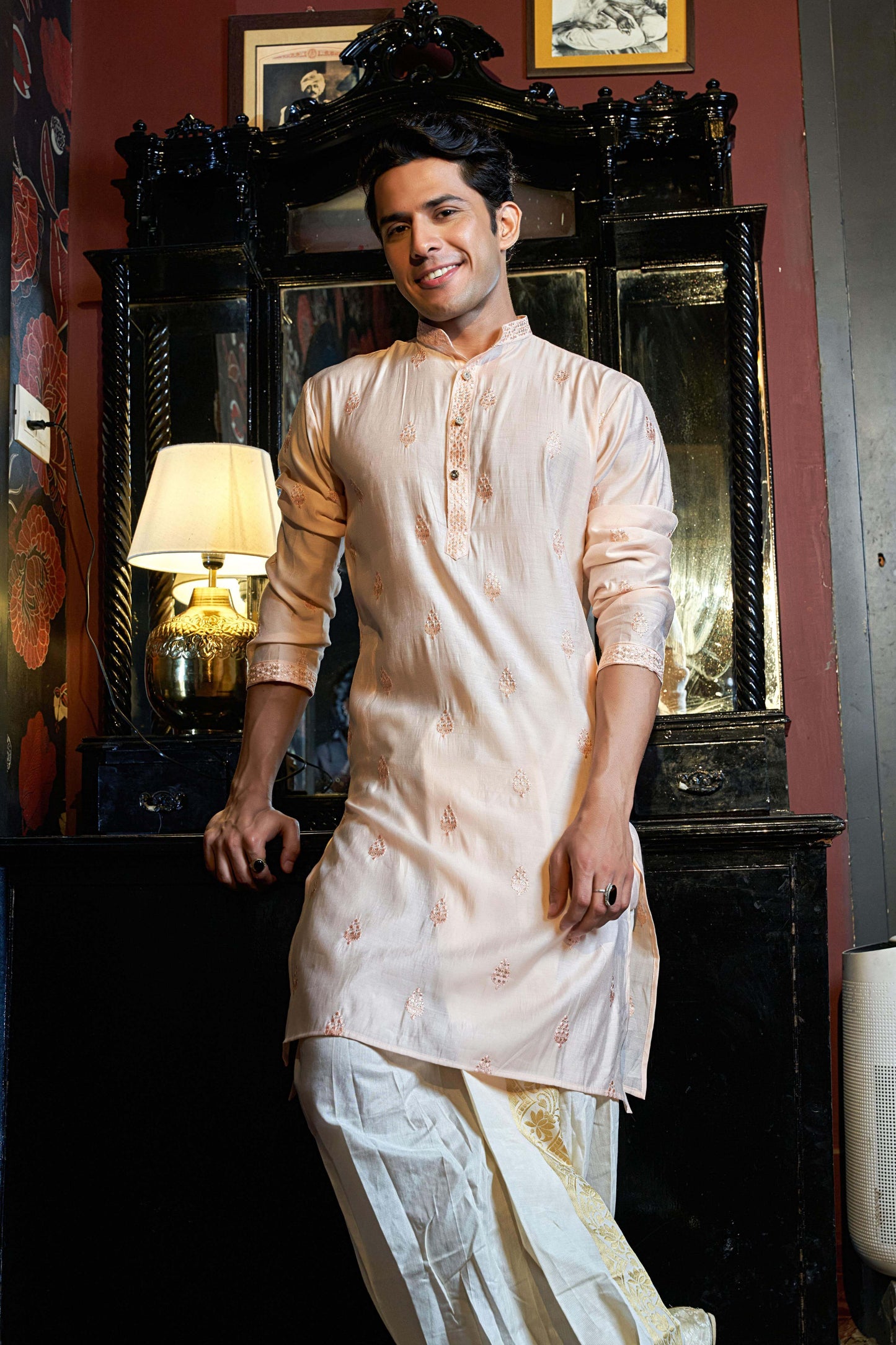 Indian man wearing a pink embroidery work long kurta. featuring a beautiful mirror and lamp