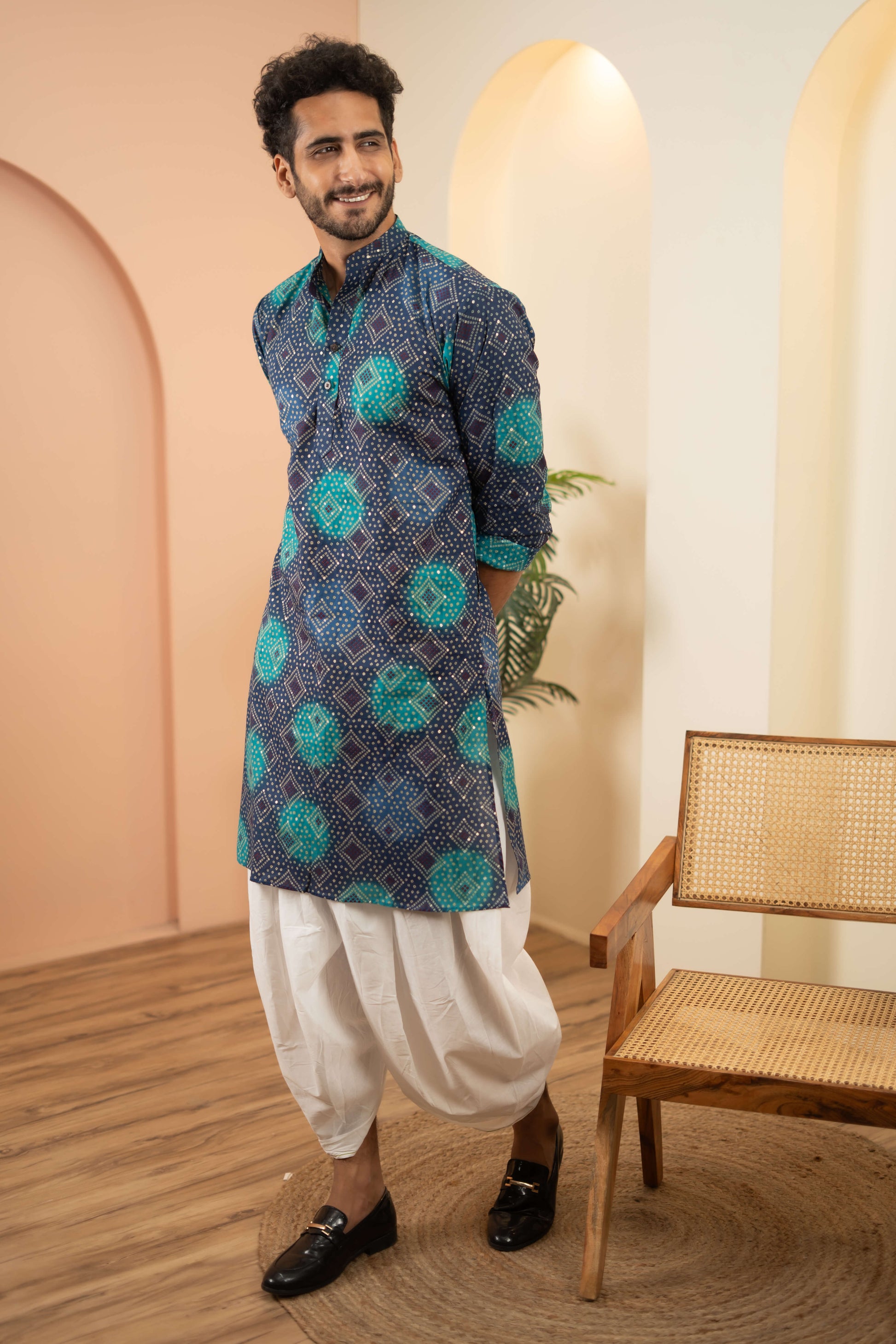 An Indian man wearing a bandhani print long kurta and dhoti. showcasing a vibrant ethnic look. 