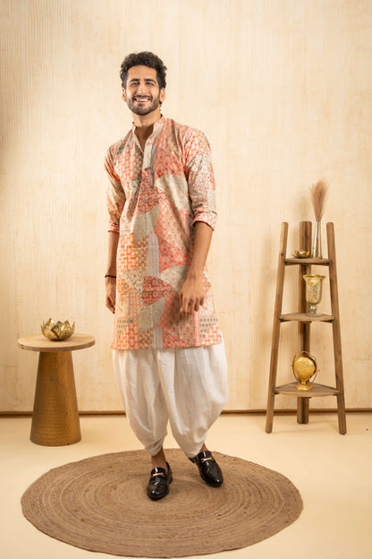 A man dressed in traditional Indian attire stands confidently in a beautifully decorated room.