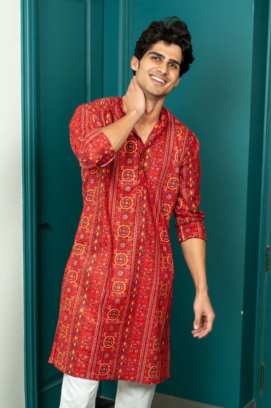 A person in a red kurta with a teal background.